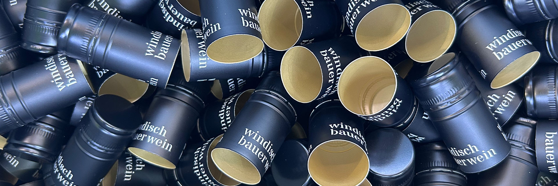 Viele schwarze Schraubverschlüsse mit dem Windischbauer Logo